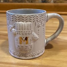 a white coffee mug with the letter m on it's side and a bear face