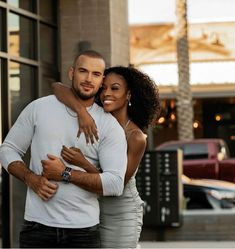 a man and woman hugging each other in front of a building