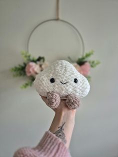 a person holding a small stuffed animal in front of a white wall with flowers on it