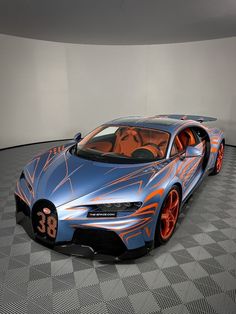 a blue and orange bugatti car on a checkered floor in a room