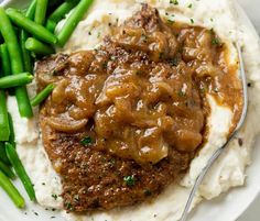 a white plate topped with mashed potatoes covered in gravy and green beans