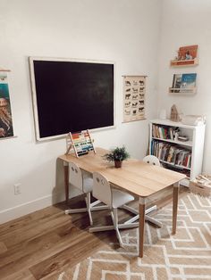 a room with a desk, bookshelf and chalkboard on the wall in it