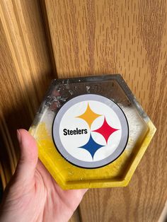 a hand is holding up a yellow and white magnet with the pittsburgh football logo on it