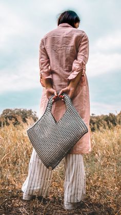 a woman carrying a black and white bag in a field