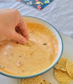 a person dipping tortilla chips into a bowl