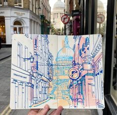 a hand holding up an open book in front of a building with a dome on it