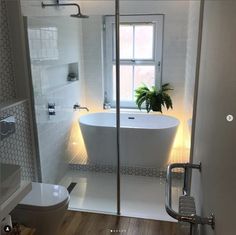 a white bath tub sitting inside of a bathroom next to a toilet under a window