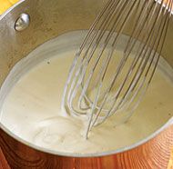 the whisk is being stirred into the batter in a large metal bowl on top of a wooden table