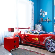 a child's bedroom decorated in red and blue with a sports car bedding