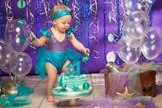 a baby girl is playing with her birthday cake