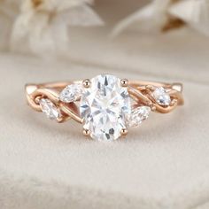 a rose gold engagement ring with three pear shaped diamonds on the band and an oval center stone