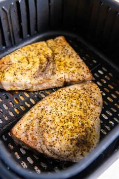 two pieces of chicken sitting on top of a black grill grate next to each other