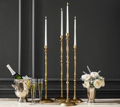 a table topped with candles and vases filled with flowers next to wine glasses on top of a counter