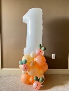 a number one balloon sitting on the floor next to an orange and white ballon