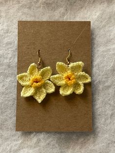 two crocheted flower earrings on top of a piece of brown paper next to a pair of scissors