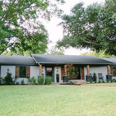 a gray brick house sitting on top of a lush green field