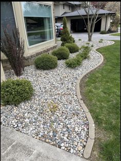 a house with rocks and grass in front of the window, next to a driveway