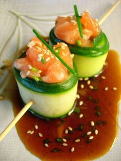 two cucumbers with smoked salmon and sesame seeds are on a white plate, garnished with chopsticks