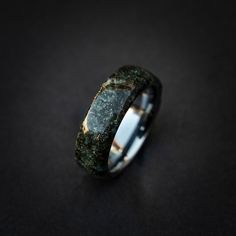 a wedding band with green mossy stone inlays on the inside of it