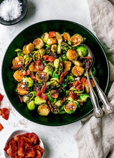 brussel sprouts with tomatoes and bacon in a black bowl on a white table