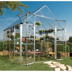 a small greenhouse with plants growing inside and on the roof, in a garden area