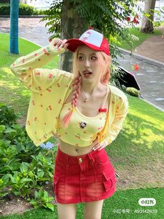 a woman in a yellow top and red skirt posing for the camera with an umbrella behind her