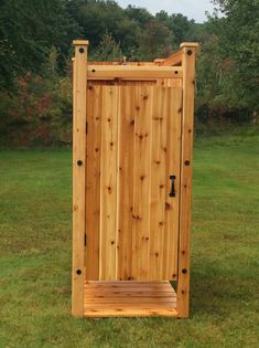 a wooden outhouse sitting on top of a lush green field