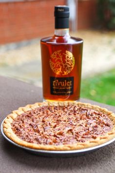 a pizza sitting on top of a table next to a bottle of liquor