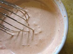 a whisk in a white bowl filled with batter