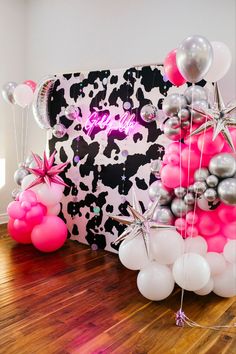 balloons and streamers are on the floor in front of a cow print backdrop