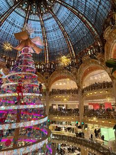 a large christmas tree in the middle of a shopping mall with lights on it's ceiling