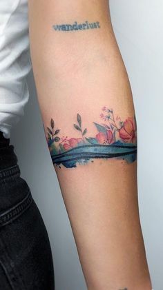 a woman's arm with flowers on it and the word tattoo written in black ink