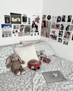 there is a stuffed animal on the bed with many pictures on the wall behind it