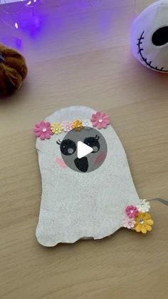 a paper cut out of a ghost with flowers on its head sitting on a table