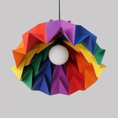 an origami light hanging from the ceiling with multiple colored paper pieces on it