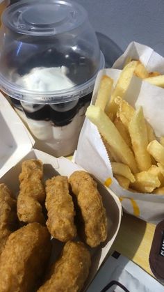 some fried food is sitting on a table next to a container of yogurt and fries