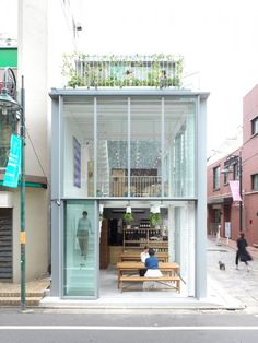 a person sitting on a bench in front of a building with glass walls and windows