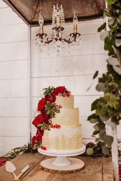 a wedding cake sitting on top of a wooden table next to a chandelier