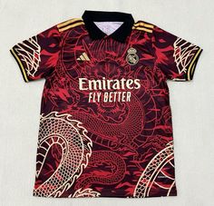 a red and black soccer jersey with dragon designs on the chest, in front of a white background