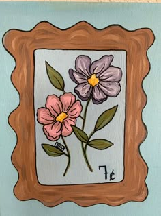 a painting of flowers in a wooden frame on a light blue wall with the letter f