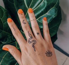 a woman's hand with tattoos on it and an orange manicured nail polish