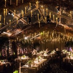 the inside of a tent is lit up with candles and greenery for an elegant wedding reception