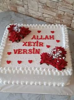 a cake that has been decorated with red flowers and hearts on it, sitting on a table in front of a brick wall