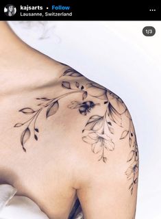 the back of a woman's shoulder with flowers and leaves tattooed on her arm