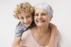 an older woman holding a young boy in her arms, both looking at the camera