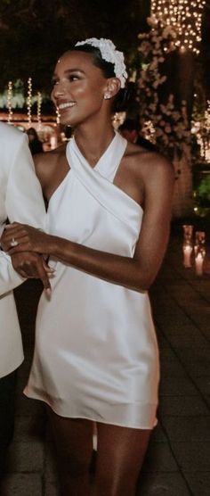 two women in white dresses standing next to each other with candles on the ground behind them