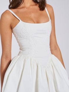 a woman wearing a white dress with straps