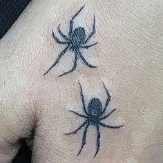 a hand with two black spider tattoos on it