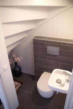 a white toilet sitting next to a sink in a bathroom under a slanted ceiling