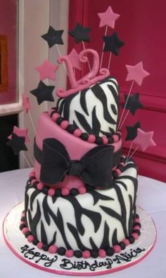 a three tiered cake with zebra print and pink icing, decorated with stars